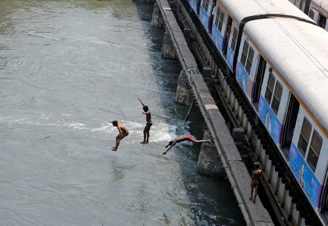 Boys jump from a railway bridge in a creek to cool off in Mumbai, March 31, 2017. (Photo by Shailesh Andrade/Reuters)