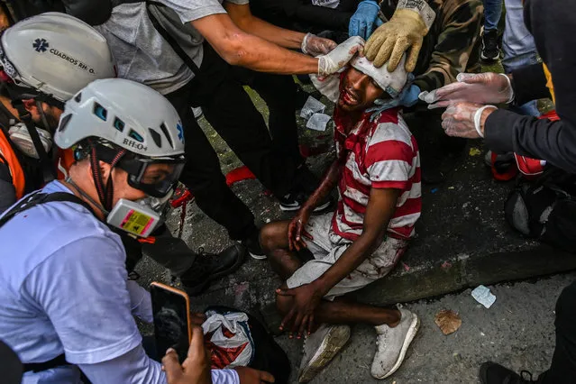 A man injured during clashes with riot police is assisted by paramedics during a protest against the government in Medellin, Colombia, on June 28, 2021. (Photo by Joaquín Sarmiento/AFP Photo)