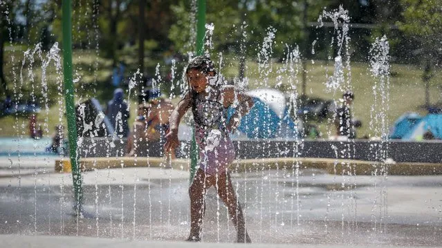 A young girl runs through a fountain at a splash park trying to beat the heat in Calgary, Alberta, Wednesday, June 30, 2021. Environment Canada warns the torrid heat wave that has settled over much of Western Canada won't lift for days. (Photo by Jeff McIntosh/The Canadian Press via AP Photo)