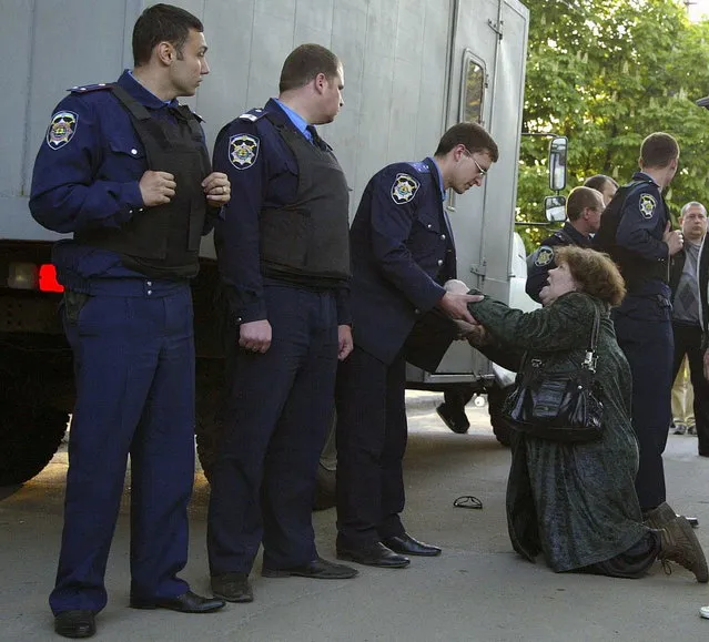 A mother of one of the detained  pro-Russian activists pleads with police officers to free her son, in Mariupol, Ukraine, Wednesday, May 7, 2014. Angry pro-Russian protesters in the city of Mariupol in eastern Ukraine blocked police forces on Wednesday from moving at least 14 detained activists from a police station to face a judge as required by law. About 50 people, relatives of those detained, surrounded a police truck and stopped it from reaching the police station. (Photo by Alexander Ermochenko/AP Photo)