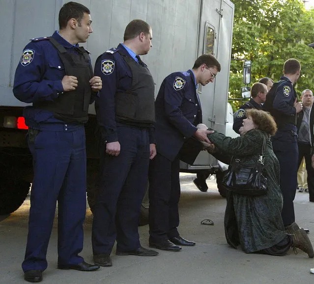 A mother of one of the detained pro-Russian activists pleads with police officers to free her son, in Mariupol, Ukraine, Wednesday, May 7, 2014. Angry pro-Russian protesters in the city of Mariupol in eastern Ukraine blocked police forces on Wednesday from moving at least 14 detained activists from a police station to face a judge as required by law. About 50 people, relatives of those detained, surrounded a police truck and stopped it from reaching the police station. (Photo by Alexander Ermochenko/AP Photo)