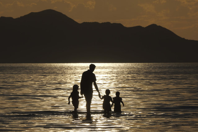 A family walks in the water during sunset at the Great Salt Lake Thursday June 13, 2024, near Salt Lake City. (Photo by Rick Bowmer/AP Photo)