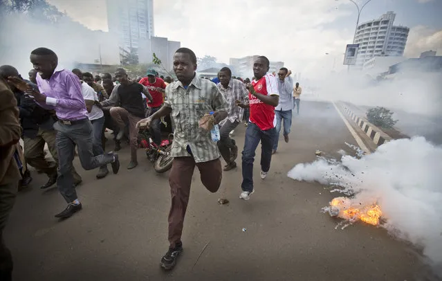 Opposition supporters, some carrying rocks, flee from exploding tear gas grenades fired by riot police, during a protest in downtown Nairobi, Kenya Monday, May 16, 2016. (Photo by Ben Curtis/AP Photo)