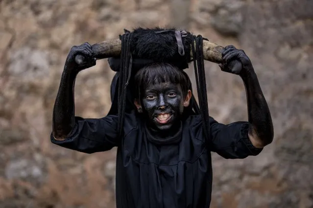 A reveler, dressed as “Diablos de Luzon” or Luzon Devil's, covered in oil and soot carrying bull horns on his heads and cowbells on belts representing the devil poses for a picture during carnival celebrations in the small village of Luzon, Spain, Saturday, February 26, 2022. (Photo by Manu Fernandez/AP Photo)