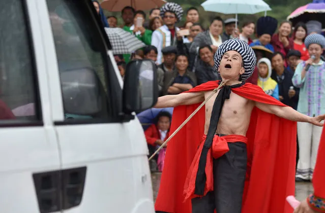 An ethnic Miao artist performs folk stunt as he drags a car with his throat during a local festival celebration event in Tongren, Guizhou province, China May 3, 2017. (Photo by Reuters/Stringer)