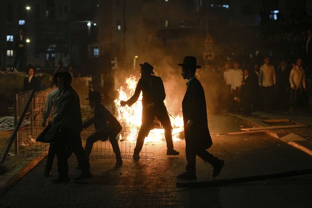 Ultra-Orthodox Jewish men burn trash during a protest against army recruitment in Jerusalem on Sunday, June 30, 2024. Israel's Supreme Court last week ordered the government to begin drafting ultra-Orthodox men into the army, a landmark ruling seeking to end a system that has allowed them to avoid enlistment into compulsory military service. (Photo by Ohad Zwigenberg/AP Photo)