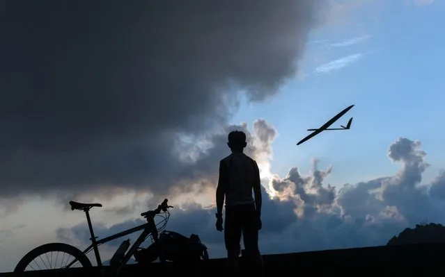 A cyclist enjoys the views of Hong Kong from Kowloon Peak as a remote controlled glider flies by in Hong Kong, China, 24 April 2019. Kowloon Peak or Fei Ngo Shan is a 602 m (1,975 ft) tall hill in the northeast corner of New Kowloon, Hong Kong. (Photo by Jerome Favre/EPA/EFE)