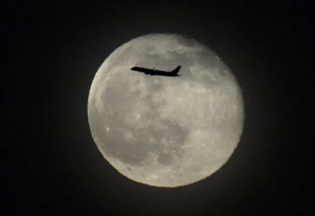 A jetliner takes off from San Francisco International Airport in front a full moon over San Francisco Bay in San Francisco, California, USA, 15 May 2014. (Photo by John G. Mabanglo/EPA)