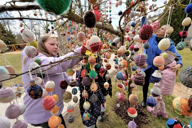 People decorate a tree with Easter eggs in the kindergarten in Seduva, Lithuania on April 11, 2022. (Photo by Ints Kalnins/Reuters)