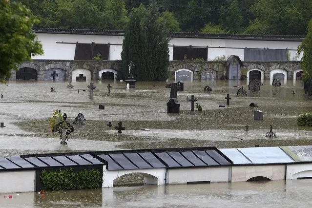 Gravestones are partially submerged by flood water at a cemetery in Schaerding, Upper Austria June 3, 2013. REUTERS/Michaela Rehle