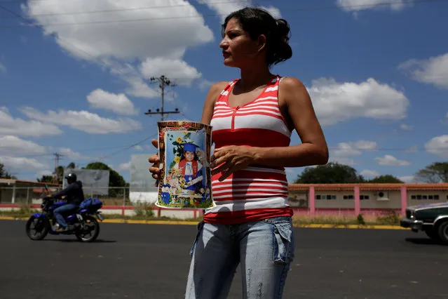 An aunt of Eliannys Vivas collects money to pay a loan used for the funeral of Eliannys, who died from diphtheria, along a main street in Pariaguan, Venezuela January 26, 2017. (Photo by Marco Bello/Reuters)