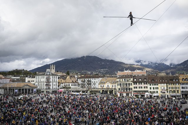 The tightrope walker of the Basinga Company, Tatiana-Mosio Bongonga, crosses the market square of Vevey, in Vevey, Switzerland, Saturday April 9, 2022, on a 180-metre long, 20 m high cable during the show “Ligne Ouverte”, on the occasion of the celebration of the link between the population and the performing arts organised by the Theatre le Reflet. (Photo by Gabriel Monnet/Keystone via AP Photo)