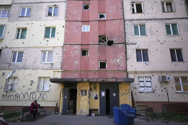 A resident sits outside a house ruined by shelling in Irpin, outskirts of Kyiv, Ukraine, Tuesday, May 24, 2022. (Photo by Natacha Pisarenko/AP Photo)