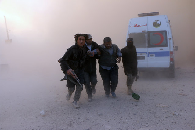 Fighters from the al-Qaida group in the Levant, Al-Nusra Front, help a wounded man following a reported barrel bomb attack by government forces in the Al-Muasalat area in the northern Syrian city of Aleppo on November 6, 2014. (Photo by Fadi al-Halabi/AFP Photo)
