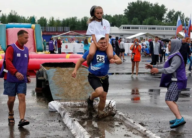 A man carries his wife over an obstacle while competing in the Wife Carrying Championship to mark City Day in Krasnoyarsk, Siberia, Russia, June 25, 2016. (Photo by Ilya Naymushin/Reuters)