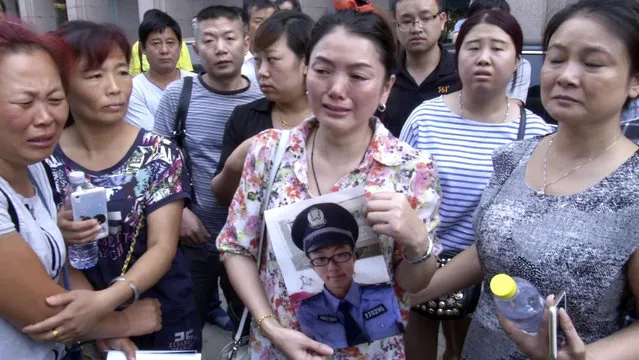 In this image taken from a video footage from AP Video, a woman holds up a photo of her son, a missing firefighter, outside a hotel where officials held a daily media conferences in northeastern China's Tianjin municipality Sunday, August 16, 2015. Angry relatives of the missing firefighters and local residents whose homes are destroyed by the blasts showed up at a government news conference Sunday to demand information and accountability. (Photo by AP Video via AP Photo)