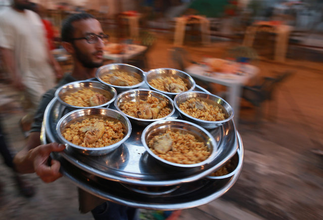 A volunteer carries food to tables set up by a charity as people wait to eat their Iftar (breaking of fast) meal during the holy fasting month of Ramadan in Benghazi, Libya,  June 29, 2016. (Photo by Esam Omran al-Fetori/Reuters)