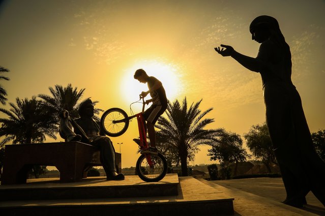 A boy makes an acrobatics show with his bike during sunset in Baghdad, Iraq on June 10, 2022. Iraqi war victimsâ young boys choose the bike show as their social activity with these kinds of activities, they look at life from a different perspective. They prefer Abu Nuas Park and Iraqi Culture Rescue Memorial Park as meeting points. (Photo by Murtadha Al-Sudani/Anadolu Agency via Getty Images)