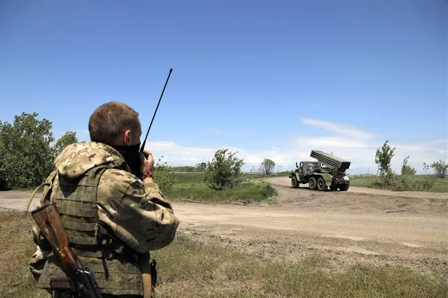 A Donetsk People's Republic militia serviceman speak on a communication device prior to fire with a multiple rocket launcher from its position not far from Panteleimonivka, in territory under the government of the Donetsk People's Republic, eastern Ukraine, Saturday, May 28, 2022. (Photo by Alexei Alexandrov/AP Photo)