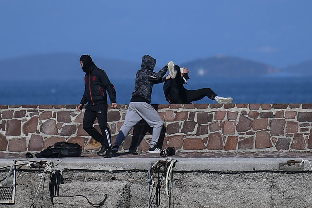 A journalist (R) is attacked by residents who are trying to prevent migrants from disembarking on the Greek island of Lesbos, on March 1, 2020. The United Nation called on March 1 for calm and urged states to refrain from “excessive” force, as thousands of migrants have flooded to Turkey's border with Greece in a bid to enter the EU. A massive influx of migrants swelled along the border over the weekend after Turkey's President Recep Tayyip Erdogan threatened to open its frontier to Europe as tensions mount over its deepening conflict in Syria. (Photo by AFP Photo/Stringer)