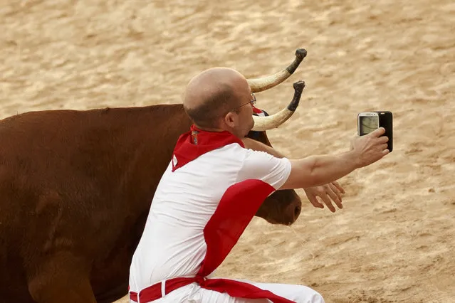 A reveler is tossed as he tries to get a snapshot next to a brave cow in the bullring during a daily amusement event after the running of the bulls in the 2016 San Fermin fiestas in Pamplona, Spain, Thursday, July 7, 2016. Revelers from around the world turned out here to kick off the festival with a messy party in the Pamplona town square, one day before the first of eight days of the running of the bulls. (Photo by Daniel Ochoa de Olza/AP Photo)