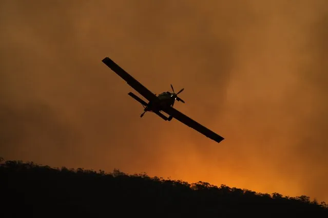 A small aircraft is pictured after dumping fire retardant behind houses at the foot of Mount Tennant as the fire front of the Orroral Valley fire creeps through the Namadgi National Park on January 30, 2020 in Canberra, Australia. Firefighters are on high alert as heatwave conditions in New South Wales and the ACT increase the fire danger across areas which have already been affected by bushfire in recent months. (Photo by Brook Mitchell/Getty Images)