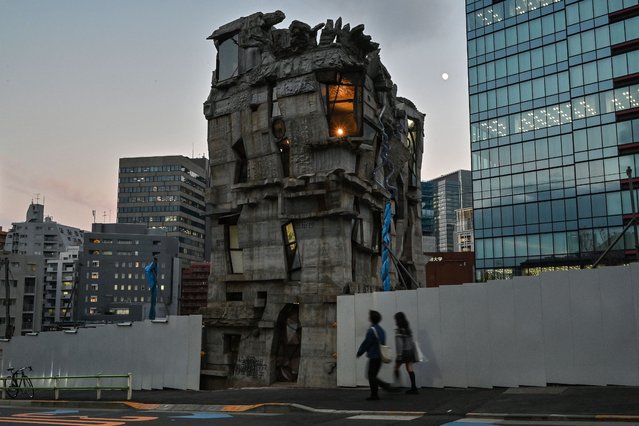This photo taken on November 13, 2024 shows pedestrians walking past the four-storey Arimaston Building by Japanese architect Keisuke Oka in the Mita area of Minato Ward in Tokyo. Passers-by stop and stare at the ramshackle, hand-built concrete tower that looks like it has been lifted right out of a Japanese animation and dropped onto a real-life Tokyo street. Oka started construction in 2005. Apart from the help of a few friends, he made the entire building himself by hand. (Photo by Richard A. Brooks/AFP Photo)