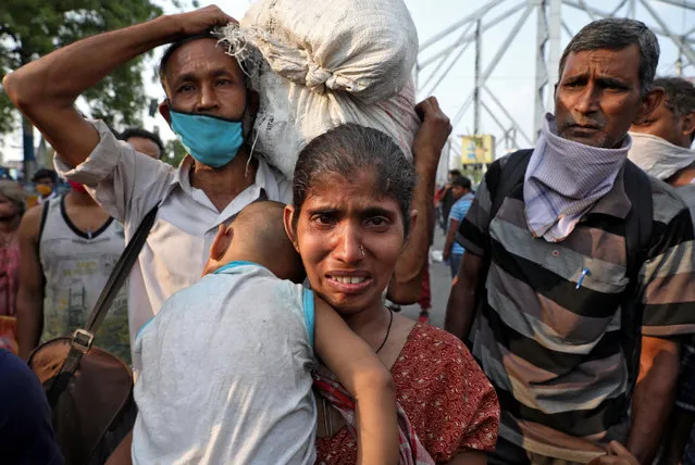 A migrant worker holding her baby cries after she missed out on receiving free food outside Howrah railway station after India ordered a 21-day nationwide lockdown to limit the spreading of coronavirus disease (COVID-19), in Kolkata, India, March 25, 2020. (Photo by Rupak De Chowdhuri/Reuters)