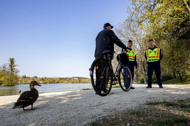 Police officers on patrol to control the observance of the lockdown speak with a man at the boating pond in Szombathely, Hungary, Good Friday, April 10, 2020. The Hungarian government prolonged the lockdown on April 10 for an undetermined period of time in an attempt to curb the spread of of novel coronavirus COVID-19. (Photo by Gyorgy Varga/MTI via AP Photo)