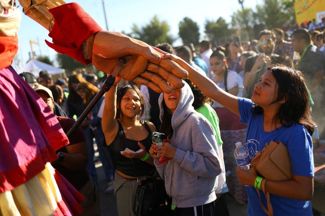 People gather around “Little Amal”, a 12-foot-tall puppet depicting a 10-year-old Syrian refugee, during her journey along the US-Mexico border at Plaza de la Mexicanidad in Ciudad Juarez, Mexico on October 26, 2023. (Photo by Jose Luis Gonzalez/Reuters)