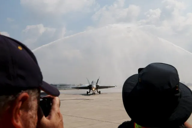 Members of the media photograph a water salute for a CF-188 Hornet from the 425 Alouettes, Tactical Fighter Squadron, 3 Wing Bagotville, Quebec, during media day for the Canadian International Air Show at Pearson Airport in Toronto, Ontario, September 3, 2015. (Photo by Louis Nastro/Reuters)