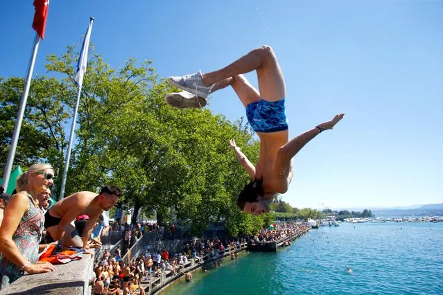 A reveller jumps to cool-off into Lake Zurich during the Street Parade dance music event in Zurich, Switzerland on August 13, 2022. (Photo by Arnd Wiegmann/Reuters)