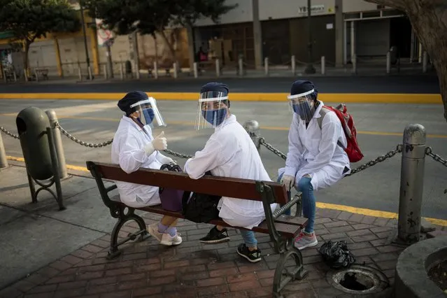 Pharmacy workers wait to enter their store in downtown Lima, Peru, Friday, May 8, 2020, amid the new coronavirus pandemic. (Photo by Rodrigo Abd/AP Photo)