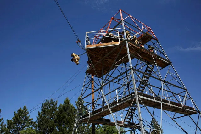 A smokejumper recruit trains by jumping from a large tower while attached to a zip line at the North Cascades Smokejumper Base in Winthrop, Washington, U.S., June 6, 2016. (Photo by David Ryder/Reuters)