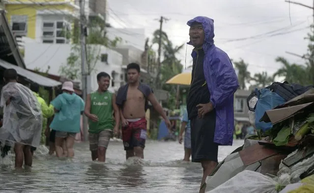 Residents wade along a flooded village caused by typhoon Vongfong as it passed by Sorsogon province, eastern Philippines on Friday May 15, 2020. More than 150,000 people were riding out a weakening typhoon in emergency shelters in the Philippines on Friday after a mass evacuation that was complicated and slowed by the coronavirus. (Photo by Melchor Hilotin/AP Photo)