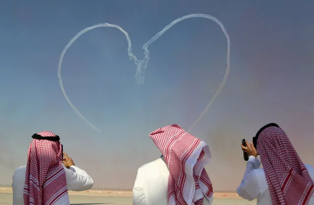 People take pictures as the UAE Air Force’s Al Fursan aerobatics team performs during the Dubai airshow, United Arab Emirates, Monday, November 13, 2017. (Photo by Satish Kumar/Reuters)