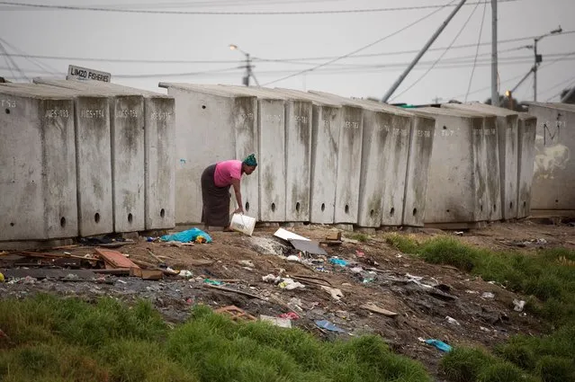 A woman throws out waste water next to a line of toilets in an informal settlement in Langa, a mostly impoverished township, about 10km from the centre of Cape Town, on November 12, 2017. (Photo by Rodger Bosch/AFP Photo)