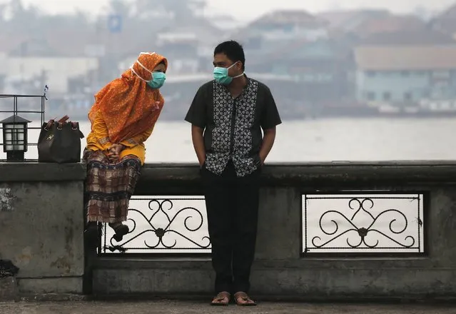 A couple, wearing face masks to protect themselves from the haze, talk near Musi River in Palembang, on the Indonesian island of Sumatra, September 20, 2015. (Photo by Reuters/Beawiharta)