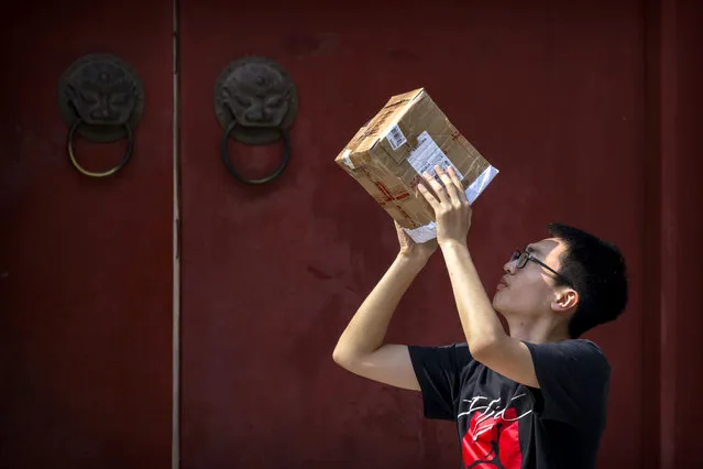 A man uses a homemade viewer to look at a partial solar eclipse near the historic Bell Tower in Beijing, Sunday, June 21, 2020. (Photo by Mark Schiefelbein/AP Photo)