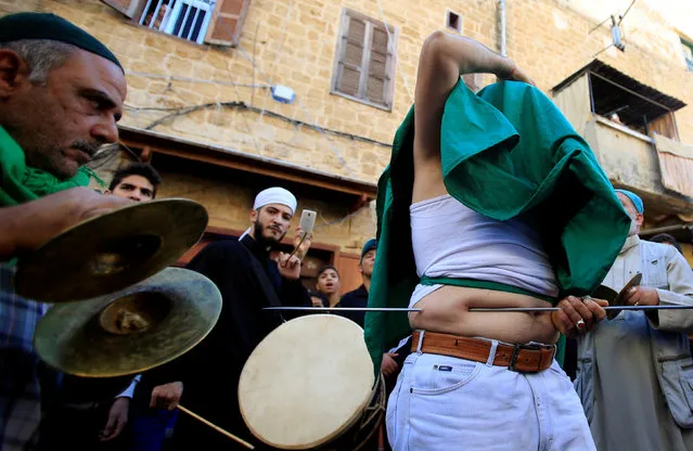 A member of a Lebanese Sufi Muslim group pushes a skewer through himself as part of annual Sufi ritual to commemorate the birth of Prophet Mohammed at the port city of Sidon, Lebanon November 30, 2017. (Photo by Ali Hashisho/Reuters)