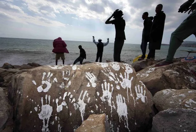 A group of Sudanese and Eritrean migrants are seen in silhouette near a rock with white hand prints on the seawall at the Saint Ludovic border crossing on the Mediterranean Sea between Vintimiglia, Italy and Menton, France, September 23, 2015. European Union leaders meet in Brussels at an emergency summit on Wednesday to patch up bitter divisions over the migration crisis. (Photo by Eric Gaillard/Reuters)
