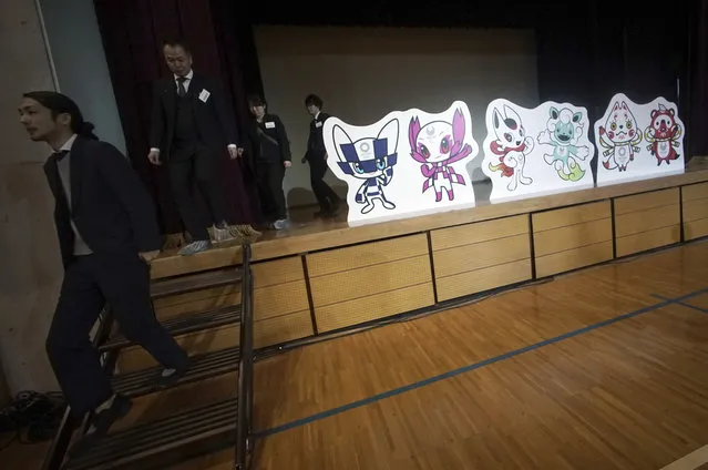 Staffs walk near the shortlisted three mascot design sets which each contain one mascot for the Tokyo 2020 Olympic Games and one for the Paralympic Games at an elementary school in Tokyo Thursday, December 7, 2017. Organizers of the 2020 Tokyo Olympics and Paralympics on Wednesday unveiled three sets of designs for the Games' mascots. The three sets were selected from 2,042 entries submitted by the public. Schoolchildren across Japan will review the shortlisted designs with their classes casting a single vote in favor of one of the sets. The winner will be announced on Feb. 28. (Photo by Eugene Hoshiko/AP Photo)