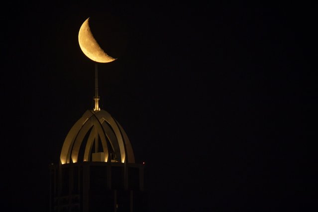 Crescent moon appears in the sky, rising above the Zaniary Tower, the highest point in the city of Erbil, Iraq on March 24, 2025. (Photo by Ahsan Mohammed Ahmed Ahmed/Anadolu via Getty Images)