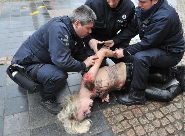 An activist of Ukraine's feminist movement Femen is taken away by the police as she demonstrates by the EU Council building where the EU-Russia summit is taking on December 21, 2012 in Brussels, Belgium. (Photo by Georges Gobet/AFP Photo)