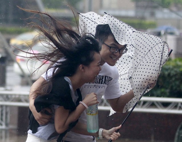 People hold onto their umbrella while walking against strong winds caused by Typhoon Dujuan in Taipei, Taiwan, September 28, 2015. (Photo by Pichi Chuang/Reuters)
