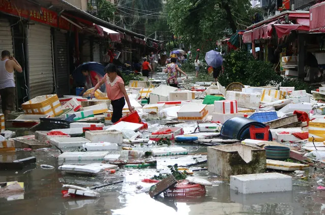 Residents clean up a flooded street in Xiamen, in China's eastern Fujian province after Typhoon Meranti made landfall on September 15, 2016. Parts of Taiwan came to a standstill on September 15 as super typhoon Meranti brought the strongest winds in 21 years, while China issued a red alert for waves as the storm bore down on the mainland. (Photo by AFP Photo/Stringer)
