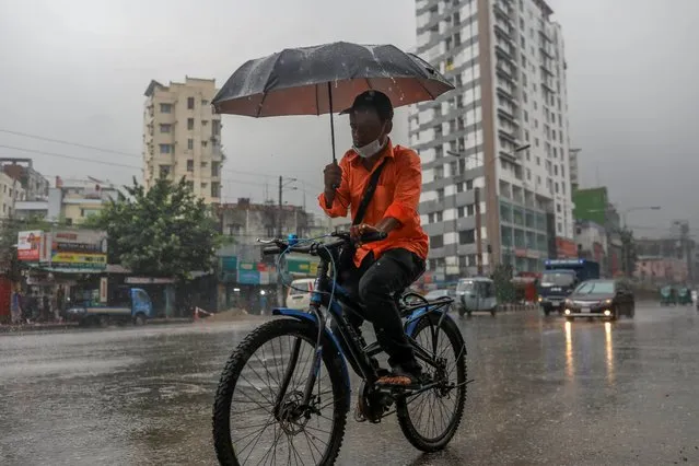 A man cycling with an umbrella and using mask protection for covid-19 in heavy rainfall day at Dhaka, Bangladesh, on September 01, 2020. (Photo by Kazi Salahuddin Razu/NurPhoto via Getty Images)