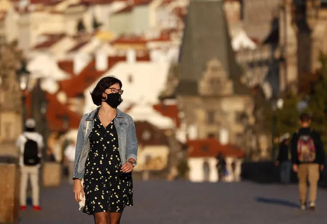 A young woman wearing a face mask walks across the medieval Charles Bridge in Prague, Czech Republic, Friday, September 18, 2020. The Czech Republic has been been facing the second wave of infections. The number of new confirmed coronavirus infections has been setting new records almost on a daily basis, currently surpassing 3,000 cases in one day for the first time. (Photo by Petr David Josek/AP Photo)