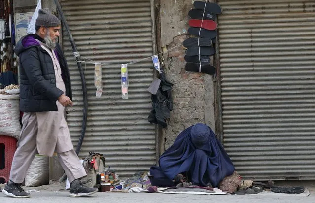 An Afghan refugee cobbler woman, right, repairs a shoe in Peshawar, Pakistan, Wednesday, January 18, 2023. (Photo by Muhammad Sajjad/AP Photo)