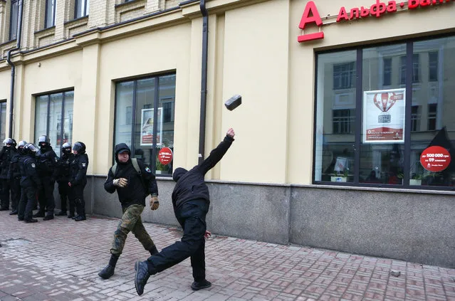 Ultra-right activists throw stones at the window of an Alfa bank office during a protest as riot police stand by and watch in central Kiev, Ukraine, Sunday, February 18, 2018.  (Photo by Efrem Lukatsky/AP Photo)